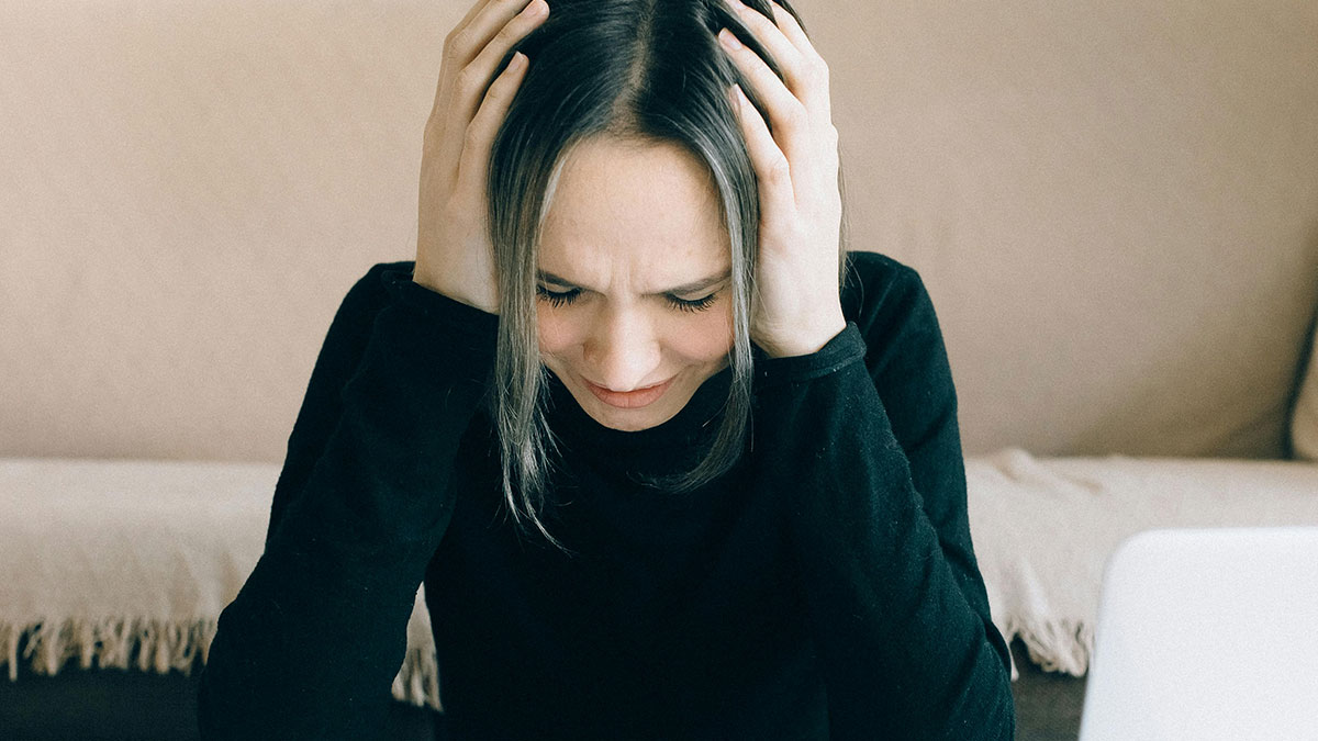 Woman stressed and holding her head, illustrating common money saving mistakes that end up costing more.