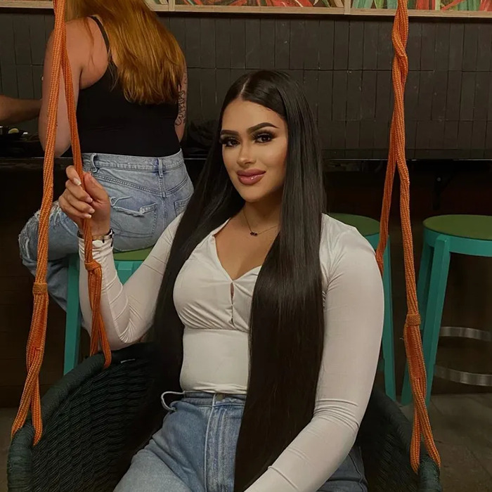 Young woman with long dark hair sitting on a swing indoors, casual outfit, smiling at the camera. Young woman with long dark hair sitting on a swing indoors, casual outfit, smiling at the camera.