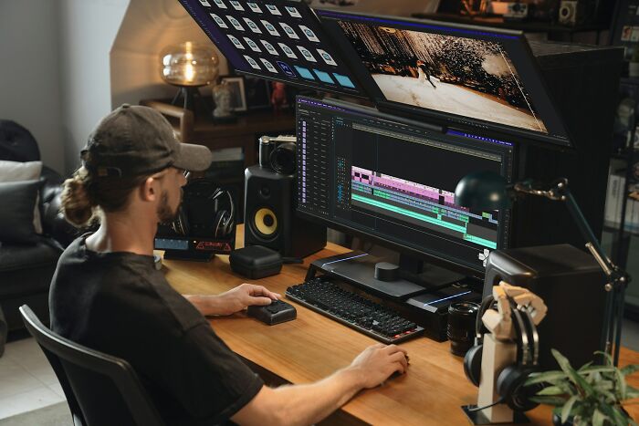 Person editing video on a dual-monitor setup in a creative workspace showing industry secrets behind closed doors.