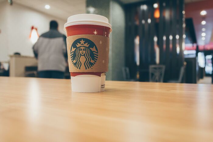 Starbucks coffee cup on a table inside a cafe, illustrating unhealthy human things related to excessive caffeine consumption.