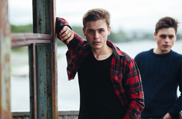 Two young men by a waterfront, one wearing a red plaid shirt, illustrating the bully bro conflict at a wedding. Two young men by a waterfront, one wearing a red plaid shirt, illustrating the bully bro conflict at a wedding.