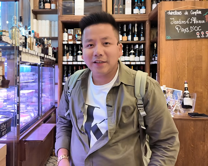 Vlogger wearing backpack inside a store, recording video unaware of sitting next to an A-list star among wine bottles. Vlogger wearing backpack inside a store, recording video unaware of sitting next to an A-list star among wine bottles.