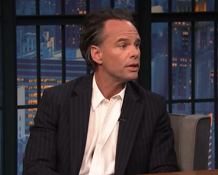 Walton Goggins in a dark pinstripe suit during a late night talk show interview, reacting to feud questions. Walton Goggins in a dark pinstripe suit during a late night talk show interview, reacting to feud questions.