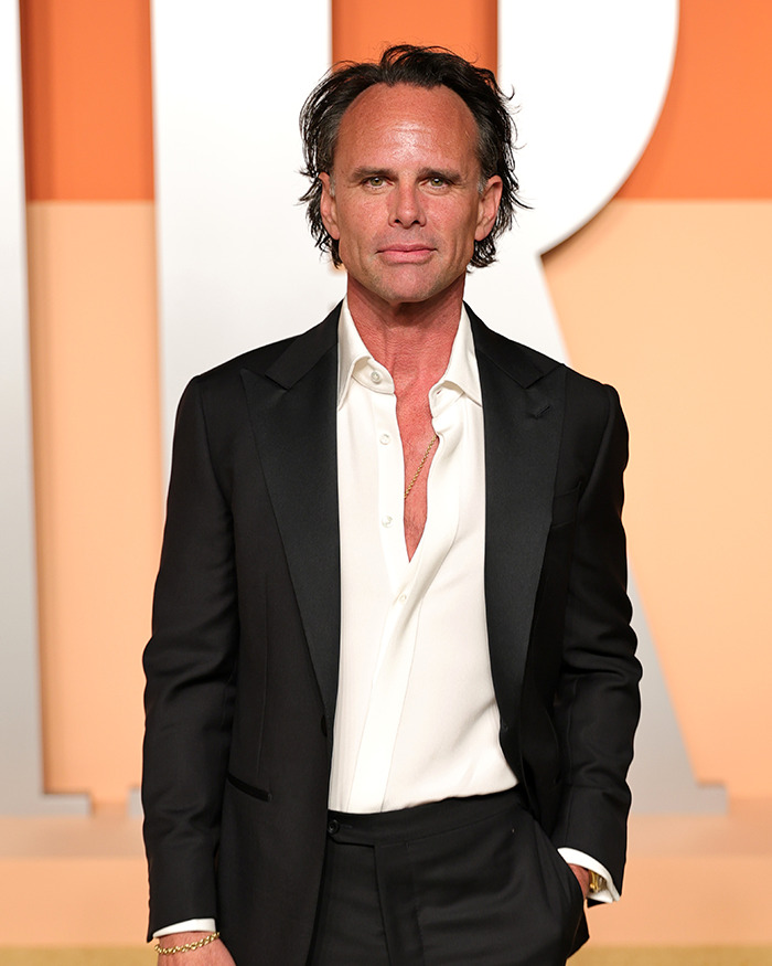 Walton Goggins in a black suit and white shirt at an event, reacting to Aimee Lou Wood feud questions. Walton Goggins in a black suit and white shirt at an event, reacting to Aimee Lou Wood feud questions.