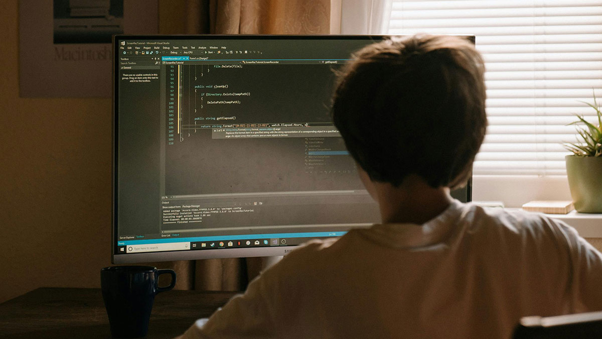 Person working on computer coding, representing freelancer tricks client into payment after suspected hacking.