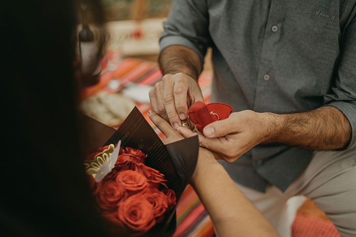 Man proposing with engagement ring to woman holding red roses, symbolizing sister’s fiancé and wedding conflict scenario.