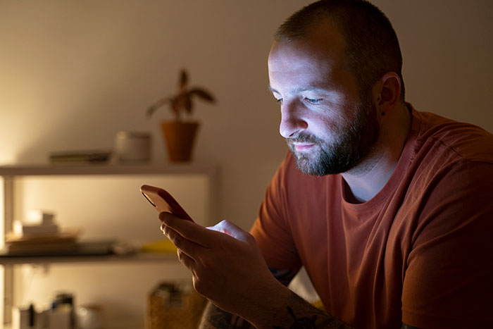 Man focused on his phone at night, highlighting a husband busy with TikTok while wife is scared and bruised in ER. Man focused on his phone at night, highlighting a husband busy with TikTok while wife is scared and bruised in ER.