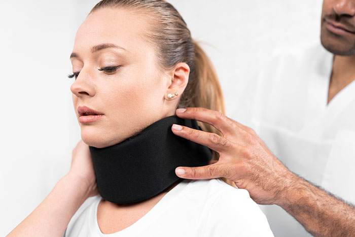 Woman scared and bruised in ER wearing a neck brace while a medical professional adjusts it during examination. Woman scared and bruised in ER wearing a neck brace while a medical professional adjusts it during examination.