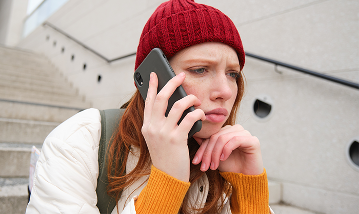 Young woman wearing a red beanie makes a serious phone call after discovering mom left little sisters at empty house. Young woman wearing a red beanie makes a serious phone call after discovering mom left little sisters at empty house.