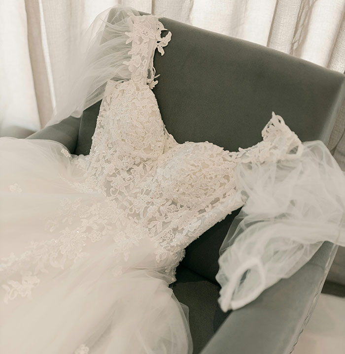 Lace wedding dress with veil laid on chair symbolizing refusal to wear fiancé’s mom’s used dress. Lace wedding dress with veil laid on chair symbolizing refusal to wear fiancé’s mom’s used dress.