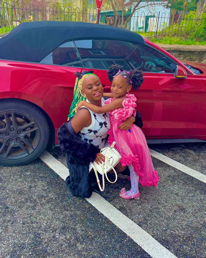 Woman with colorful hair and child in pink dress posing by a red car, unrelated to animal torture or prison time news. Woman with colorful hair and child in pink dress posing by a red car, unrelated to animal torture or prison time news.