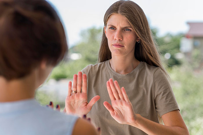 Young woman refusing to babysit step sister’s kids, showing firm hand gesture during a family disagreement outdoors. Young woman refusing to babysit step sister’s kids, showing firm hand gesture during a family disagreement outdoors.