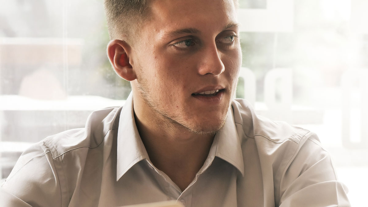 Young employee in a white shirt reacting to new boss enforcing harsh late rule at a modern office setting