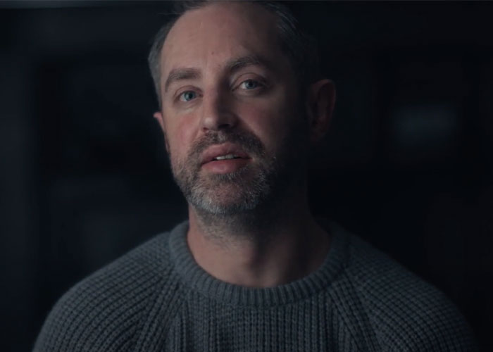 University professor with beard and gray sweater in low light discussing women and men domestic violence debate. University professor with beard and gray sweater in low light discussing women and men domestic violence debate.