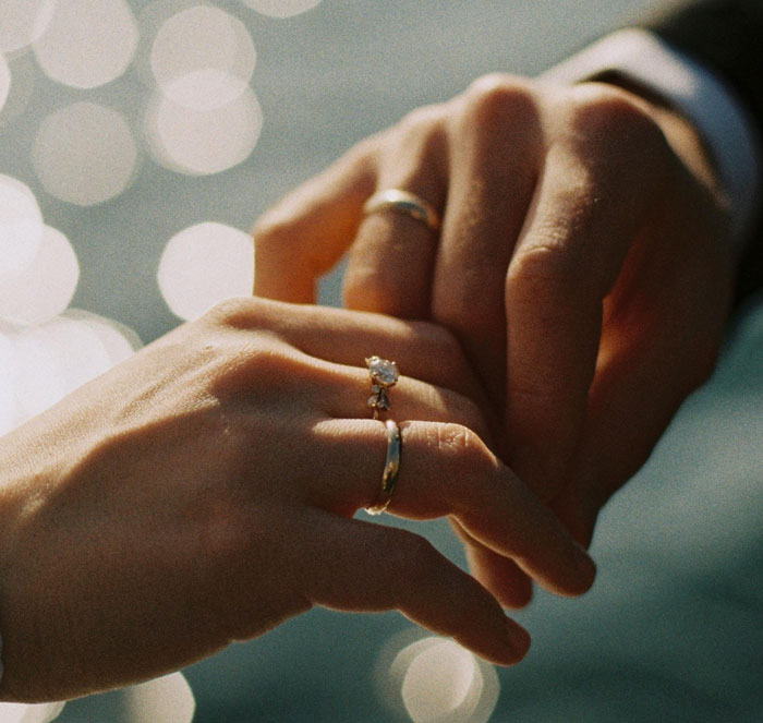 Close-up of husband and wife holding hands, both wearing wedding rings, symbolizing their relationship and emotional challenges. Close-up of husband and wife holding hands, both wearing wedding rings, symbolizing their relationship and emotional challenges.