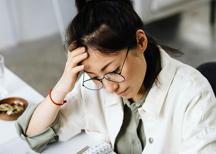 Woman with glasses looking stressed at desk, reacting to niece's college fund used for prom without permission. Woman with glasses looking stressed at desk, reacting to niece's college fund used for prom without permission.