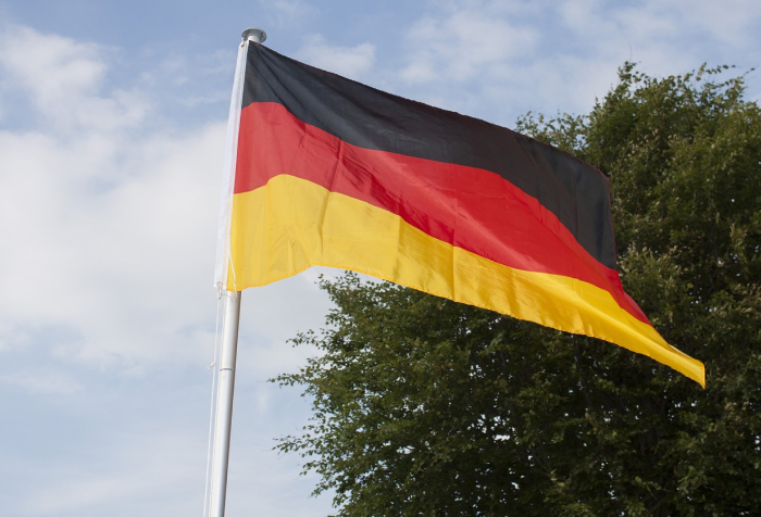 German flag waving on a pole against a partly cloudy sky, representing one of the best countries to live in 2025. German flag waving on a pole against a partly cloudy sky, representing one of the best countries to live in 2025.