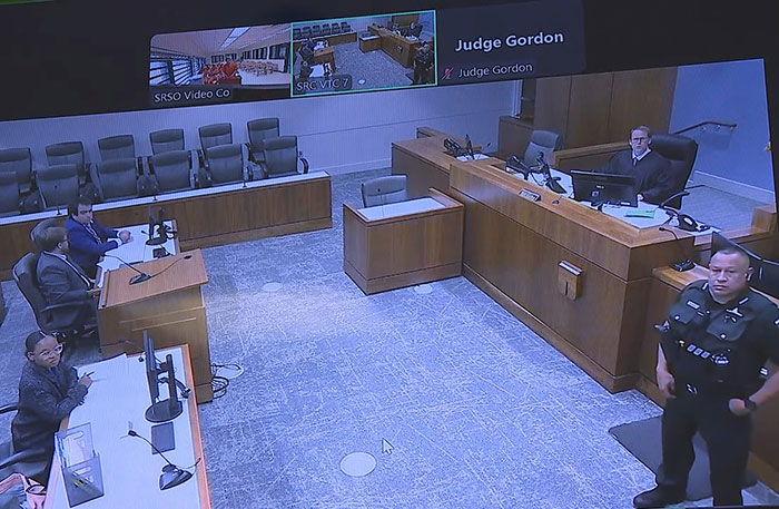 Courtroom scene showing judge, police officer, and attorneys during hearing related to captive woman's brave cry for help case. Courtroom scene showing judge, police officer, and attorneys during hearing related to captive woman's brave cry for help case.