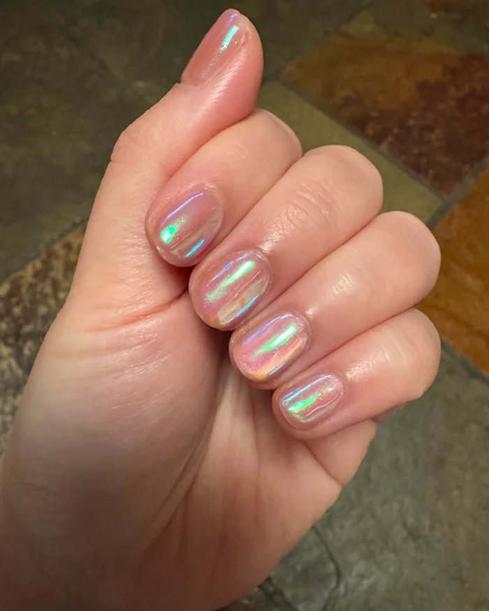 Hand showing iridescent nail polish with a glossy finish, featuring trending summer nails for 2025 style inspiration.