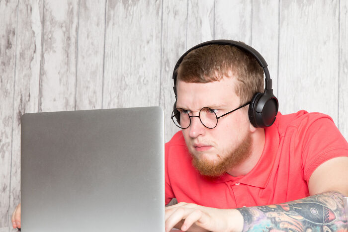 Young man with headphones and glasses focused on laptop, exploring why a good trend slowly disappeared online.