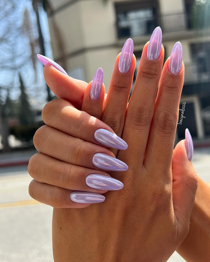 Long lavender summer nails with a glossy finish displayed outdoors in natural sunlight focusing on nail design trends.