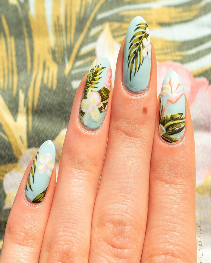 Light blue nails featuring tropical floral and leaf designs, showcasing trendy summer nails for 2025.