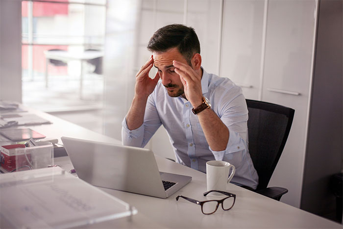 Stressed employee at desk following unworkable deployment rule, prompting management to rethink company policy. Stressed employee at desk following unworkable deployment rule, prompting management to rethink company policy.