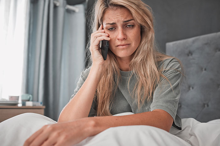 Woman with worried expression on phone, debating calling CPS after learning about niece’s home life. Woman with worried expression on phone, debating calling CPS after learning about niece’s home life.