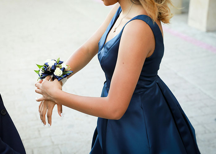Young woman in a navy blue prom dress adjusting a corsage, symbolizing college fund used for prom without permission. Young woman in a navy blue prom dress adjusting a corsage, symbolizing college fund used for prom without permission.