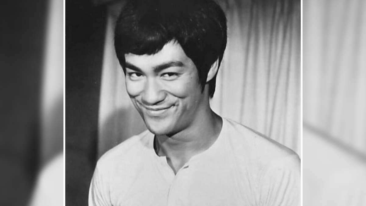 Bruce Lee smiling in a black and white portrait, representing one of the stars we lost too soon in the 20th century.