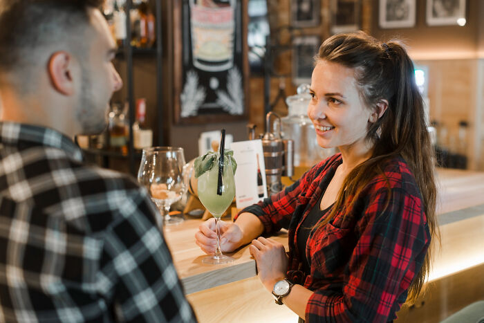A woman and man at a bar on a date, engaging in conversation with drinks, illustrating dates that went sour.