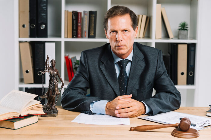 Man in a suit at a desk with legal books and a gavel, representing professions attracting the most awful people.