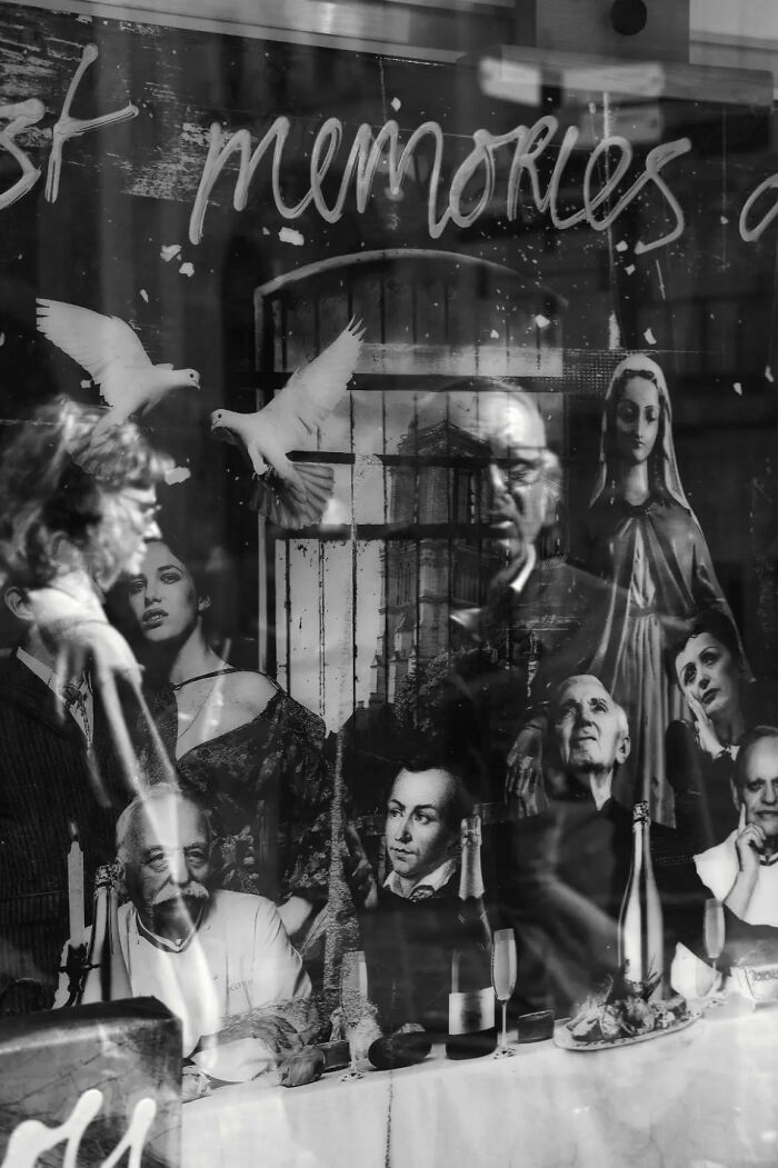 Black and white street shot capturing reflections, portraits, and two white doves conveying the poetry of everyday life moments.