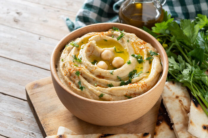 Bowl of creamy hummus garnished with olive oil, chickpeas, and parsley, a healthy best processed foods weight loss option. Bowl of creamy hummus garnished with olive oil, chickpeas, and parsley, a healthy best processed foods weight loss option.