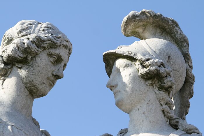 Stone statues of two remarkable mothers from history facing each other against a clear blue sky background.