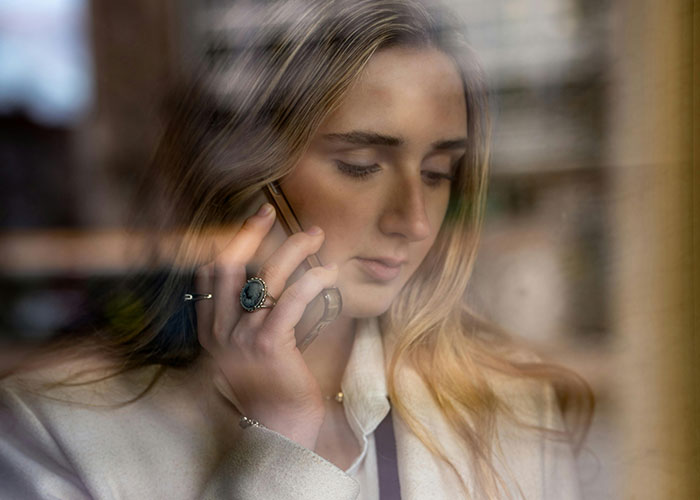Woman with concerned expression talking on phone, reflecting on college fund used for prom without permission. Woman with concerned expression talking on phone, reflecting on college fund used for prom without permission.