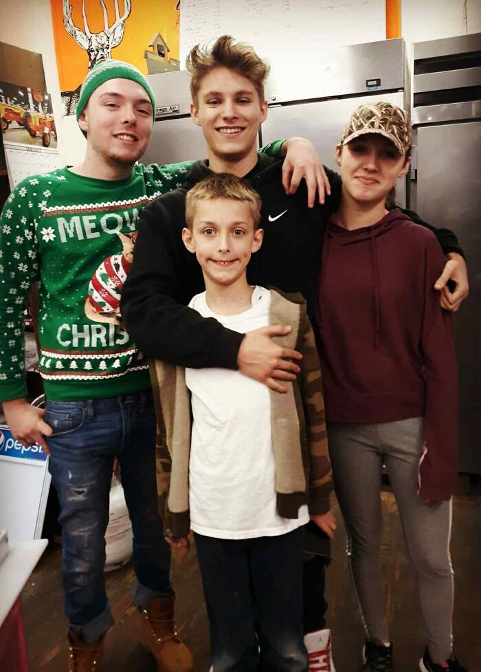 Four smiling young people standing together indoors, symbolizing connection and the legacy of a late son's heartbeat.