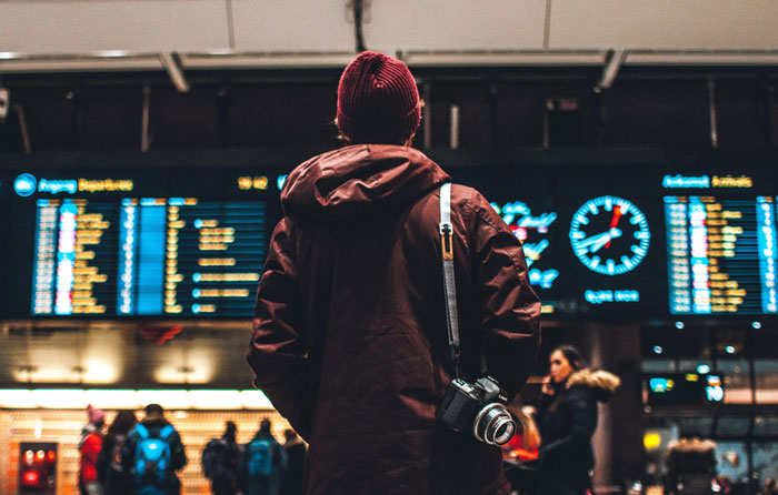 Passenger at airport with camera looks at flight board, illustrating entitled plane passenger cutting cue and getting put in place. Passenger at airport with camera looks at flight board, illustrating entitled plane passenger cutting cue and getting put in place.
