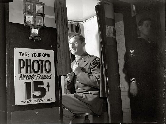 Colorized historical photo of a soldier in uniform sitting in a photo booth, showcasing magical historical photos by a viral artist.
