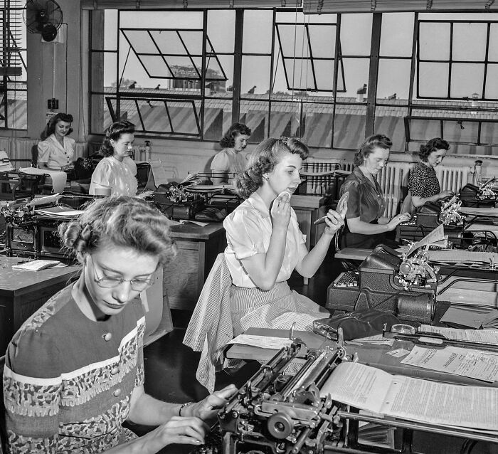 Women working in an office with typewriters in a colorized historical photo by a talented viral artist.