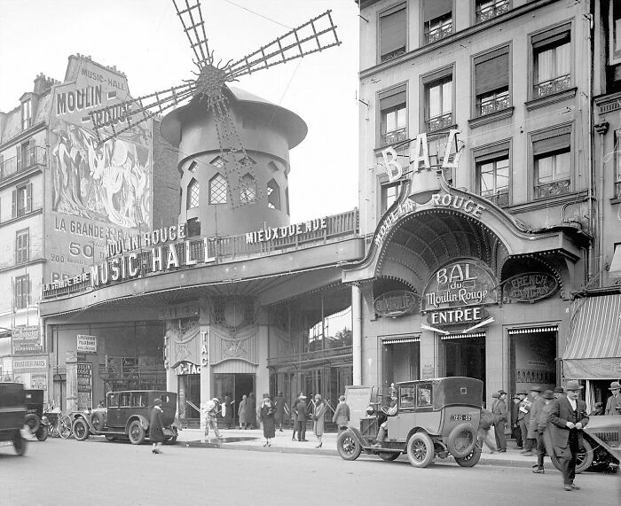Colorized historical photo of Moulin Rouge music hall and vintage cars on a Paris street from magical historical photos collection.