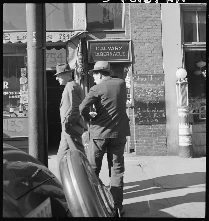 Two men in hats walking past a Calvary Tabernacle with a vintage storefront in magical historical photos colorized.