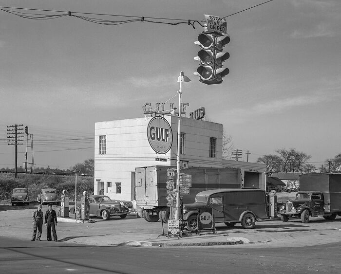 Colorized historical photo of a vintage Gulf gas station with classic cars and traffic light, showcasing magical historical art.