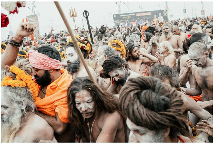 Crowded street scene in Asia with devotees covered in ash and wearing orange garments during a raw and captivating moment.