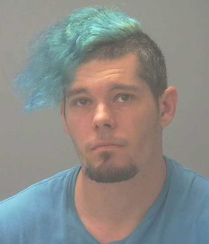 Mugshot of a man with blue hair wearing a blue shirt connected to a captive woman's brave cry for help and rescue. Mugshot of a man with blue hair wearing a blue shirt connected to a captive woman's brave cry for help and rescue.