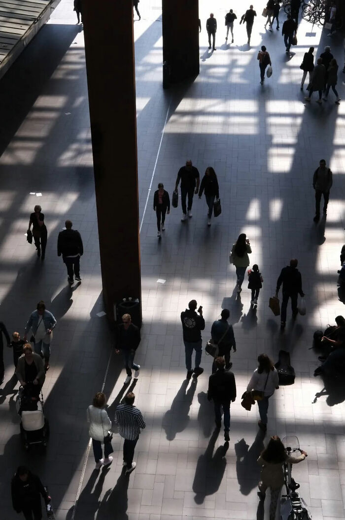 People walking in a sunlit urban space captured in a street shot showcasing the poetry of everyday life and movement.