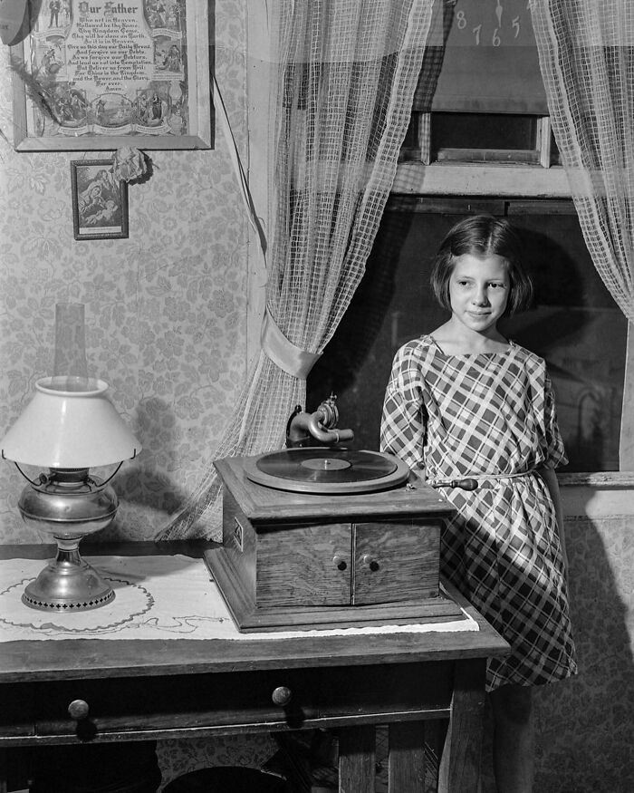 Young girl in a vintage room standing beside an old gramophone, colorized historical photo by a viral artist