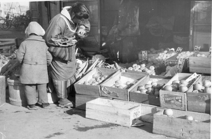 1940s housewife and child shopping for fresh produce at outdoor market, capturing daily life of housewives in the era