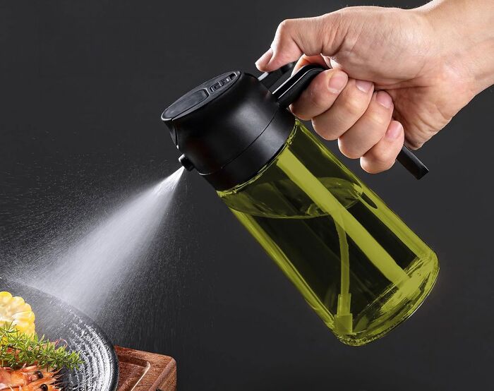 Hand spraying oil from a kitchen item spray bottle onto food, showcasing best-selling kitchen items.