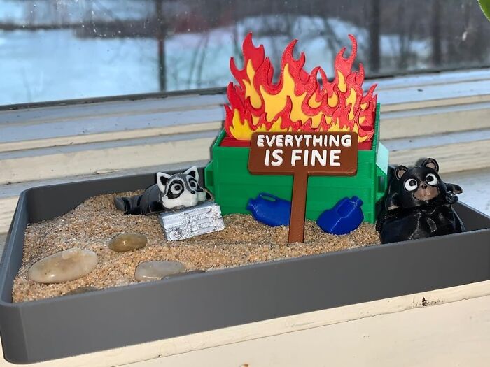Miniature sandy scene with a dumpster fire and figurines, illustrating bizarre finds related to bank account troubles.